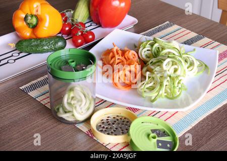 Verdure tagliate a fette e contenitore di affettatrice per verdure sul tavolo della cucina. Foto Stock