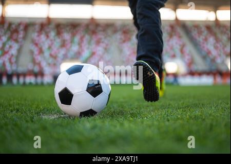 Pallone da calcio e gambe di un giovane giocatore prima di calciare la palla Foto Stock