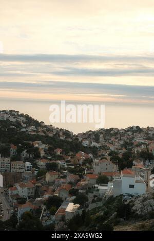 Una cittadina balneare in un ambiente montuoso, alcune case sulle colline, catturate dall'alto durante il tramonto Foto Stock