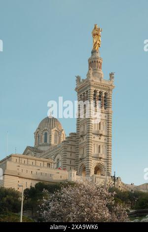 Un grande edificio con una statua dorata sulla sommità e una struttura a cupola dietro di esso Foto Stock