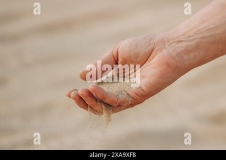 La mano di un uomo che versa sabbia nel deserto del Qatar Foto Stock