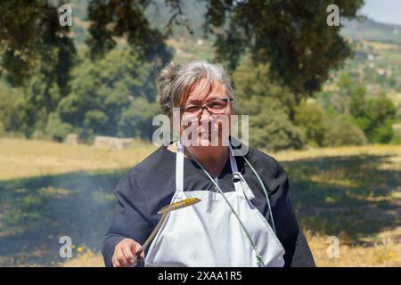 donna che cucina in grembiule bianco con una spatola in mano sorridente nel campo Foto Stock