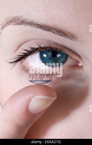 Un primo piano del viso di un giovane uomo che mette una lente a contatto sul suo occhio Foto Stock