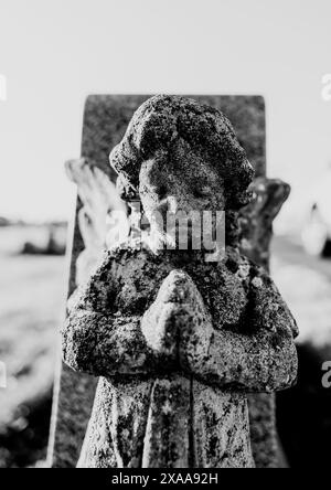 Una statua angelica simile a un bambino in un cimitero che si tiene per mano Foto Stock