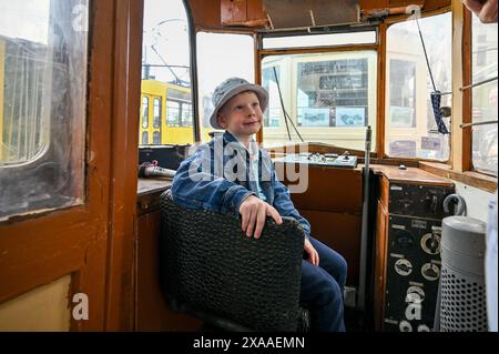LEOPOLI, UCRAINA - 1 GIUGNO 2024 - Un ragazzo siede sul cruscotto di una delle vecchie carrozze del tram durante una mostra in Piazza Dvirtseva che celebra i 130 anni di tram di Leopoli, Ucraina occidentale. Foto Stock