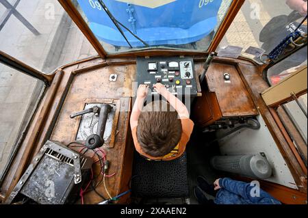 LEOPOLI, UCRAINA - 1 GIUGNO 2024 - Un ragazzo esplora il cruscotto di una delle vecchie tram durante una mostra in Piazza Dvirtseva che celebra i 130 anni di tram di Leopoli, Ucraina occidentale. Foto Stock