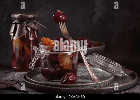 Prugne marinate con spezie in vaso di vetro sul tavolo da cucina Foto Stock