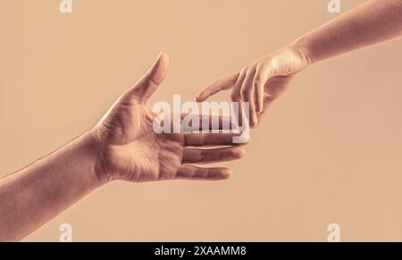 Dare una mano. Le mani dell'uomo e dei bambini si avvicinano l'una all'altra. La mano del bambino piccolo raggiunge l'uomo della mano. Concetto di aiuto per mano, supporto Foto Stock