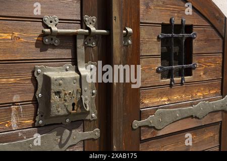 Una foto ravvicinata di un intricato blocco di ferro e di un dispositivo di chiusura su una porta in legno intemprata. Foto Stock