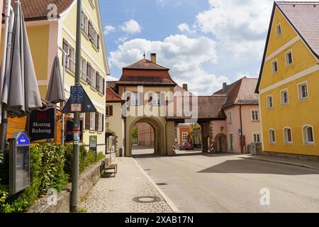 Feuchtwangen, Germania - 6 giugno 2023: Una vista pittoresca di uno storico arco in pietra e degli edifici circostanti in un'affascinante cittadina bavarese. Foto Stock