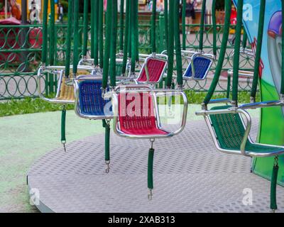 Sedie a giostra colorate vuote appese in un parco divertimenti in una giornata di sole. Foto Stock