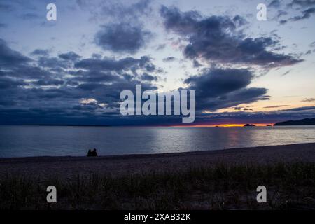 Una coppia dalla silhouette sagomata guarda un tramonto rosso scuro sull'orizzonte della baia di Agawa, situata sulle rive del lago Superior, Ontario. Foto Stock
