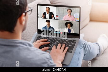 Man partecipa a riunioni aziendali online da casa, utilizzando un notebook Foto Stock