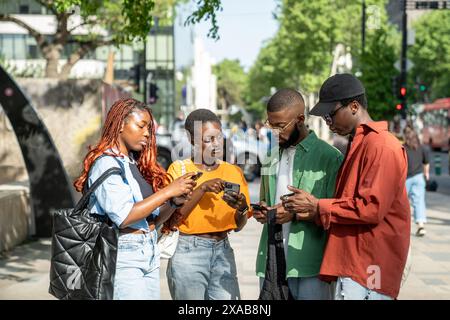 Gli amici neri usano gli smartphone non comunicano non si prestano attenzione l'uno all'altro, impantanati nei social media Foto Stock