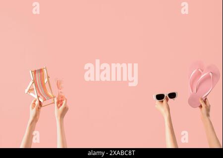 Mani femminili con infradito, mini sedia a sdraio e occhiali da sole su sfondo rosa Foto Stock