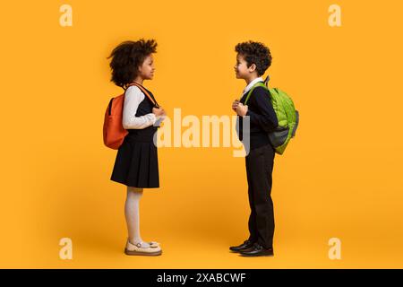 Studentesse con zaini su sfondo giallo Foto Stock