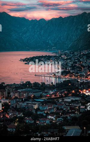 Un colorato cielo al tramonto si riflette nella baia di Cattaro a Kotos, Montenegro, il vecchio porto mediterraneo circondato da fortificazioni. Foto Stock
