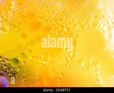 Splendido sfondo cosmetico. Bolle d'olio astratte di colore giallo dorato o fondo di siero. Foto macro di bolle d'olio e acqua Foto Stock