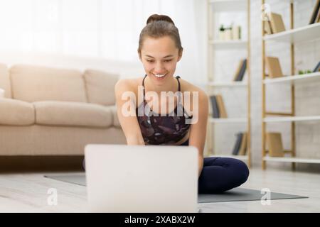 Ragazza farfalla facendo stretching e guardando lo yoga online video tutorial Foto Stock