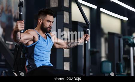 Uomo che si allena alla macchina per cavi in palestra Foto Stock