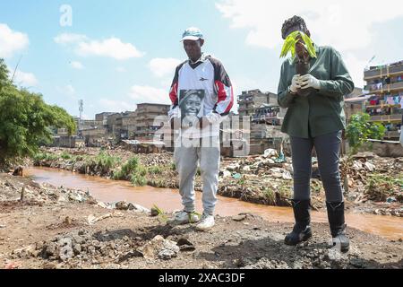 Nyaguthii Chege (R) del movimento Green Belt e Humphrey Omukuti (L) fondatore del Ghetto Farmers Mathare (GHM) un collettivo di residenti Mathare che lavorano insieme nell'agricoltura concentrando la riabilitazione del fiume Nairobi. In un momento di silenzio per ricordare le persone uccise dalle inondazioni, durante un evento di piantagione di alberi in occasione della giornata Mondiale dell'ambiente 2024 nella baraccopoli di Kiamaiko, a Nairobi, Kenya, 5 giugno 2024. La giornata mondiale dell'ambiente si celebra ogni anno il 5 giugno e incoraggia la consapevolezza e l'azione a favore della protezione dell'ambiente. Il tema del 2024 è il ripristino della terra, la desertificazione e la siccità Foto Stock