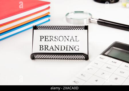 Concetto di business. Testo di branding personale su un biglietto da visita in una composizione con una calcolatrice, notebook e una lente di ingrandimento Foto Stock