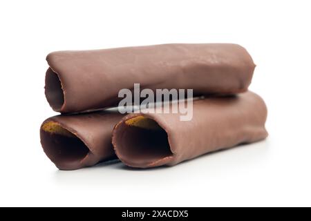 Rotoli di cialde ricoperti di cioccolato impilati uno sopra l'altro su uno sfondo bianco. I rotoli sono di colore marrone chiaro e ricoperti da un sottile strato di Foto Stock