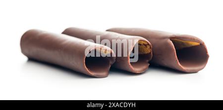 Rotoli di cialde ricoperti di cioccolato impilati uno sopra l'altro su uno sfondo bianco. I rotoli sono di colore marrone chiaro e ricoperti da un sottile strato di Foto Stock