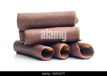 Rotoli di cialde ricoperti di cioccolato impilati uno sopra l'altro su uno sfondo bianco. I rotoli sono di colore marrone chiaro e ricoperti da un sottile strato di Foto Stock