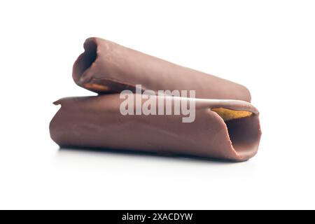 Rotoli di cialde ricoperti di cioccolato impilati uno sopra l'altro su uno sfondo bianco. I rotoli sono di colore marrone chiaro e ricoperti da un sottile strato di Foto Stock