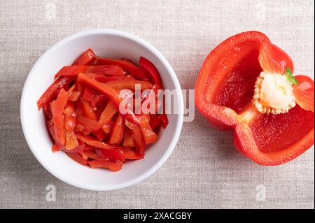 Insalata di peperoni rossi, strisce di peperoni rossi sottaceto in un recipiente bianco su tessuto di lino. Insalata di paprika, fatta di peperoni dolci a fette. Foto Stock