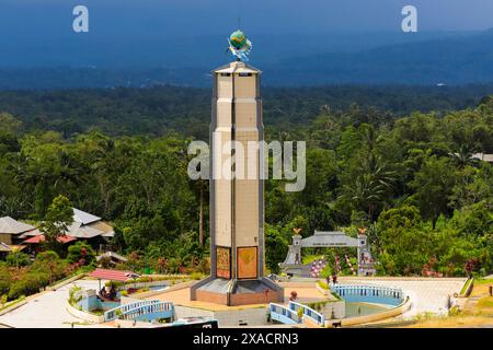 La torre a tema pace mondiale e il cielo buio tempestoso in questo parco turistico con case di culto di cinque religioni principali e campo di fumarole vulcaniche. Bukit Foto Stock