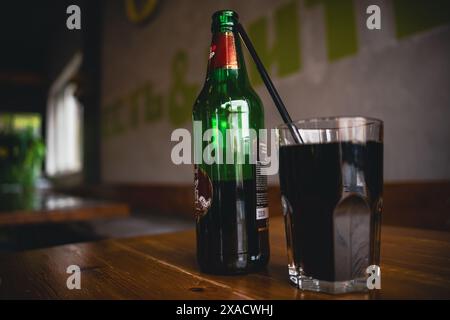 Un bicchiere di soda sta sul tavolo accanto a una bottiglia. Foto di alta qualità Foto Stock