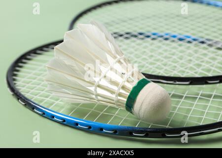 Piuma di badminton e racchette su sfondo verde, primo piano Foto Stock