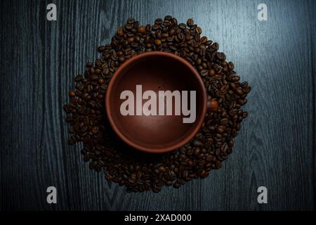 Tazza di argilla circondata da chicchi di caffè su un tavolo di legno. Foto di alta qualità Foto Stock