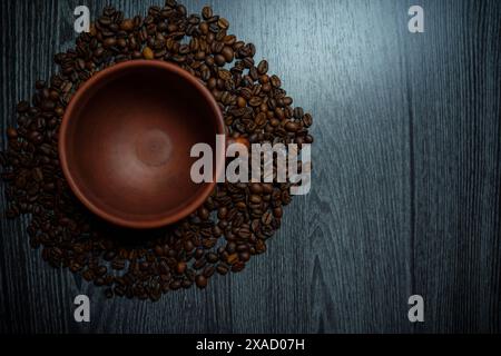 Tazza di argilla circondata da chicchi di caffè su un tavolo di legno. Foto di alta qualità Foto Stock