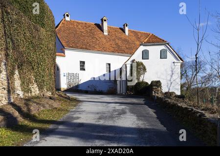 Foto di un'antica fattoria alpina tradizionale con pareti bianche e tetto in tegole rosse nelle soleggiate giornate invernali Foto Stock