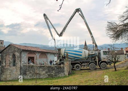 Piacenza, Italia - 16 dicembre 2015: Betoniera davanti a un rustico edificio sulle colline pronta per una colata di cemento Foto Stock