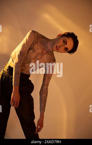 Un giovane queer con un corpo tatuato mette in posa audace su uno sfondo bianco. Foto Stock