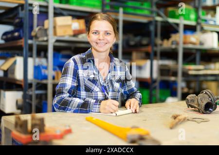 Il lavoratore del magazzino del negozio prende appunti nel notebook, tiene traccia delle merci Foto Stock