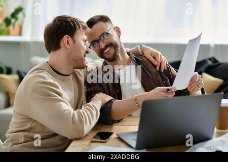 Due uomini in un'officina di design lavorano insieme su un notebook, concentrati e attenti. Foto Stock