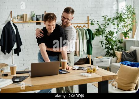 Due uomini che fanno brainstorming con passione su un notebook in un laboratorio di design alla moda. Foto Stock