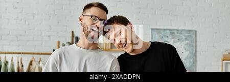 Due uomini, una coppia gay, in piedi fianco a fianco in un laboratorio di designer, discutendo e creando insieme abiti alla moda. Foto Stock