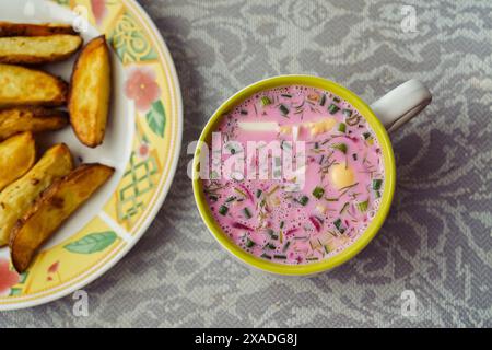 Un piatto con la tradizionale zuppa lituana fredda estiva di barbabietole e kefir Saltibarsciai o kholodnik lituano o borscht freddo con patate al forno Foto Stock