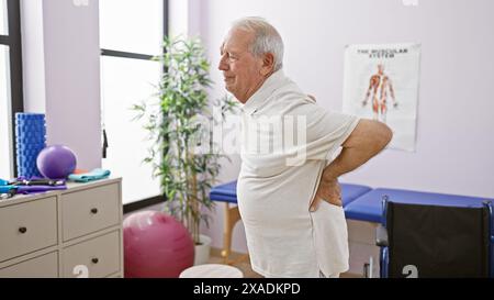 L'uomo anziano che soffre di dolori alla schiena esacerbati viene sottoposto a fisioterapia presso una clinica di riabilitazione Foto Stock