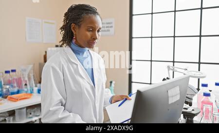 Scienziata africana che lavora in un ambiente di laboratorio, circondata da attrezzature mediche. Foto Stock