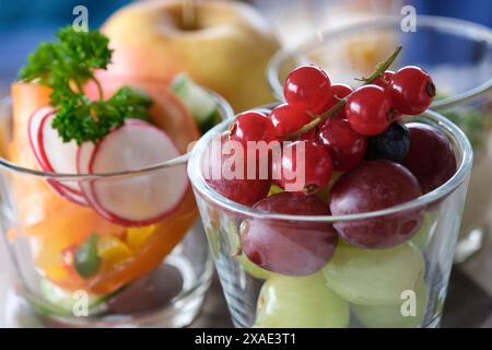 Tre piccole ciotole di vetro piene di frutta, tra cui mele, uva e ravanelli. Le ciotole sono disposte in modo che sembrino su una t Foto Stock