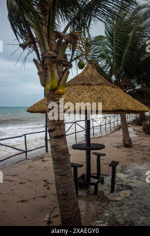 Un tavolino con sedie sotto un ombrellone di paglia, dopo un temporale sulla spiaggia di Inhassoro in Mozambico Foto Stock