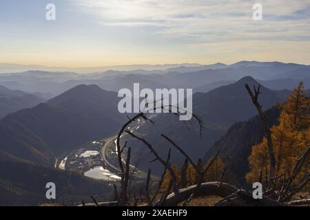 Fotografie panoramiche delle montagne alpine in una valle con fiume ed edifici al tramonto autunnale Foto Stock