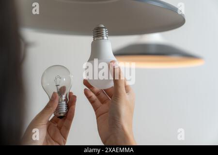 La giovane donna sta cambiando le lampadine a casa Foto Stock